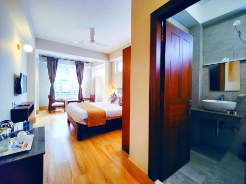a bedroom with a bed and a bathroom with a sink at Dzongkar - MG Marg - 3 Star Hotel in Gangtok