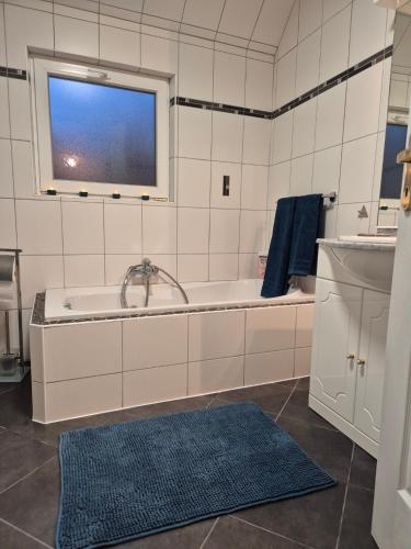 une salle de bain avec une baignoire, un lavabo et une fenêtre dans l'établissement Le linele, à Handschuheim