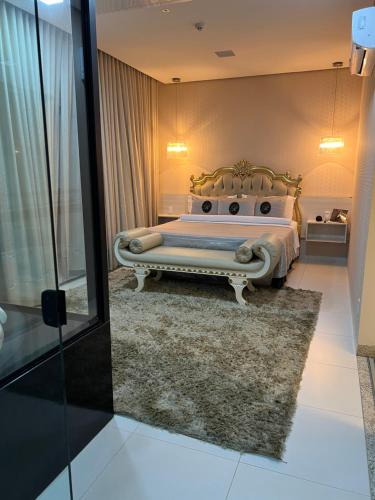 a bedroom with a bed with a bench in it at Hotel Relicário in Araguaína