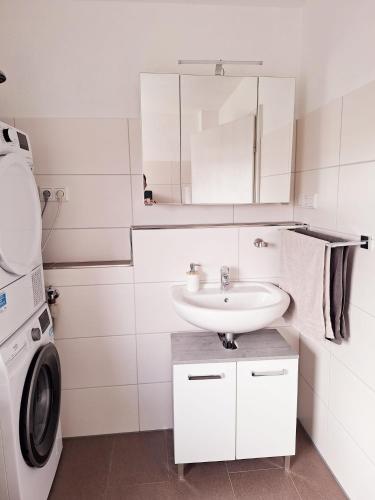a white bathroom with a sink and a washing machine at Marlerei in Marl