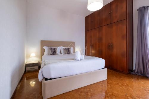 een slaapkamer met een wit bed en een houten kast bij De Casa Villa by GALMI in Estreito da Calheta