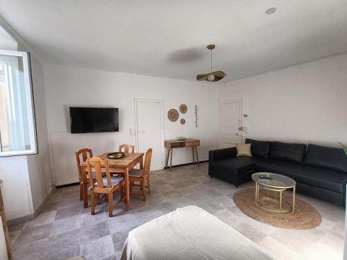 un salon avec un canapé noir et une table dans l'établissement Parenthèse Bohème Chic, à Gréoux-les-Bains