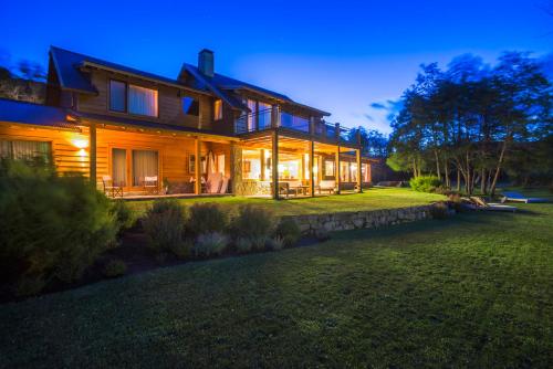 a large house with a lawn in front of it at Rio Hermoso Hotel De Montaña in San Martín de los Andes