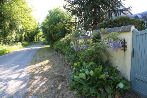 a fence with purple flowers next to a road at Gîte L'Orée de Deauville in Saint-Gâtien-des-Bois