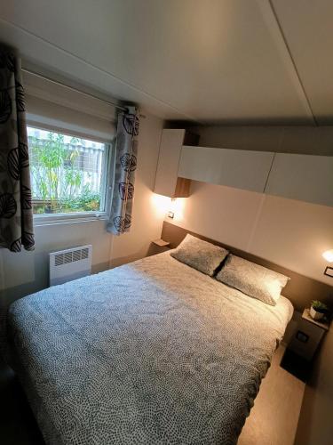 une chambre avec un grand lit et une fenêtre dans l'établissement Bungalow familial à Saint-Brevin-les-Pins avec piscine partagée_2, à Saint-Brévin-les-Pins