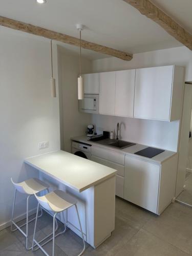 une cuisine avec des armoires blanches et une table et des chaises dans l'établissement Appartement T2 rénové climatisé, à Mandelieu-la-Napoule