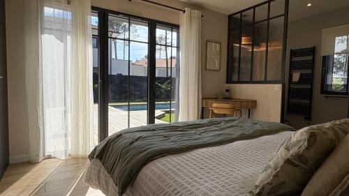 une chambre avec un lit et une porte coulissante en verre dans l'établissement Le Clos des Pins, à Andernos-les-Bains