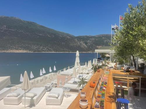 a row of white chairs and tables next to the water at Club Çapa Hotel in Kas