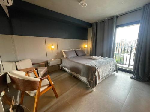 a bedroom with a bed and a chair and a window at Madrid Apartment in São Paulo
