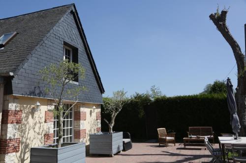 a patio with tables and chairs and a building at Gîte L'Orée de Deauville in Saint-Gâtien-des-Bois