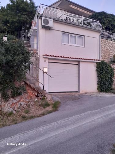 a white house with a garage on a street at Kiko 2 in Senj