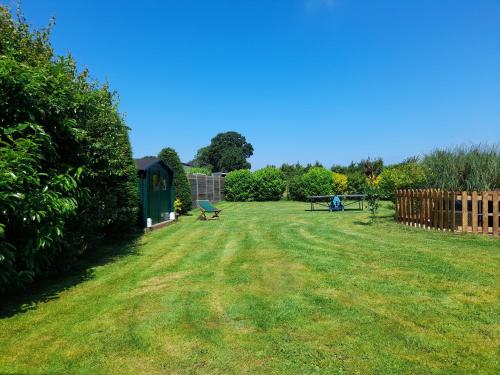 a large yard with a bench and a fence at Gîte L'Orée de Deauville in Saint-Gâtien-des-Bois