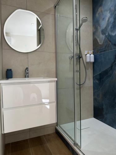 La salle de bains est pourvue d'une douche en verre avec un miroir. dans l'établissement Appartement T2 rénové climatisé, à Mandelieu-la-Napoule