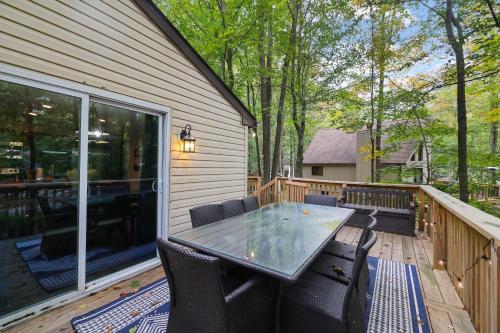 a patio with a table and chairs on a deck at Moshannon Tree-Lined Pocono Retreat w Hot Tub Firepit Pool Table in Pocono Lake