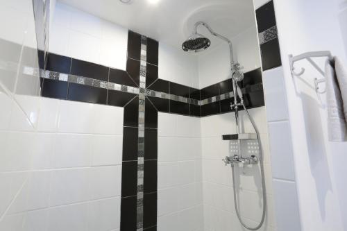 a shower with a black and white tiled wall at Gîte L'Orée de Deauville in Saint-Gâtien-des-Bois