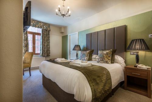 a bedroom with a large bed and a chair at The Royal Oak Hotel, Welshpool - The Coaching Inn Group in Welshpool