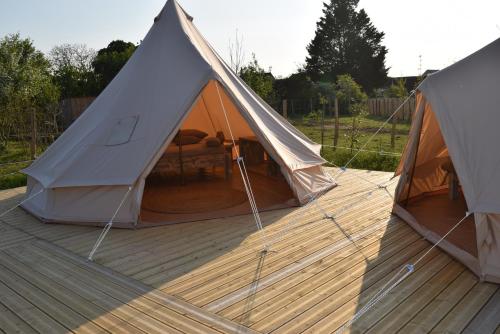 2 tentes assises sur une terrasse en bois dans l'établissement Tente Zéla, à Ambillou-Château