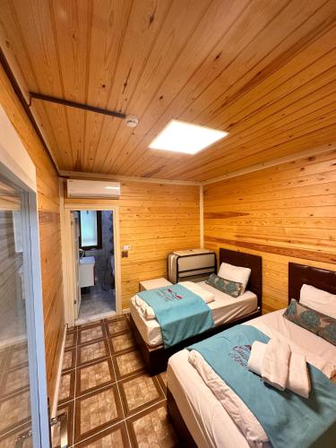 two beds in a room with wooden walls at Çakıroğlu Villa Kent in Uzungöl