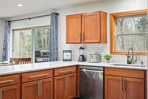 a kitchen with wooden cabinets and stainless steel appliances at Rustic-Chic Escape w Hot Tub Fireplace Nature Views Pine Woods Loft in Lehigh