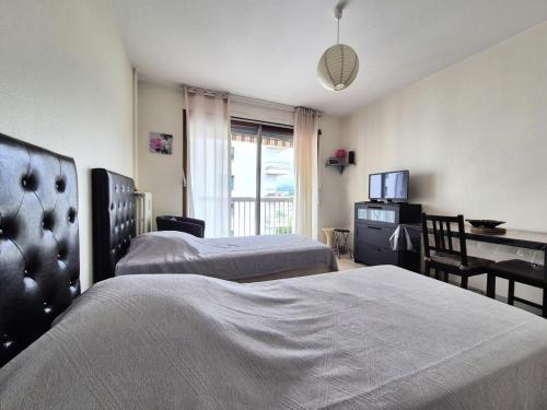 une chambre avec deux lits, un bureau et une télévision dans l'établissement Residence Victoria - Studio dans quartier calme ! MAE-7004, à Aix-les-Bains