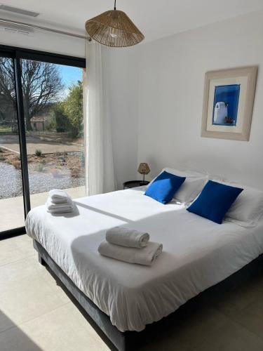 une chambre avec un grand lit blanc avec des oreillers bleus dans l'établissement Villa les Camphriers, à Grimaud