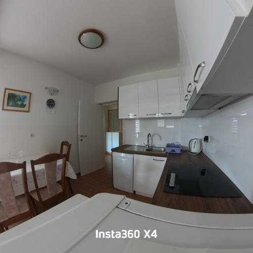 a kitchen with white cabinets and a kitchen table at Baja 2 in Lopar