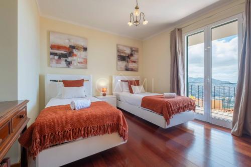 a bedroom with two beds and a large window at Casa do Pico by GALMI in Funchal