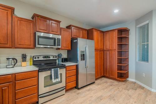 a kitchen with wooden cabinets and stainless steel appliances at Spacious 2BD - ASU - Sloan Pk - WD Parking Sleeps 8 in Tempe