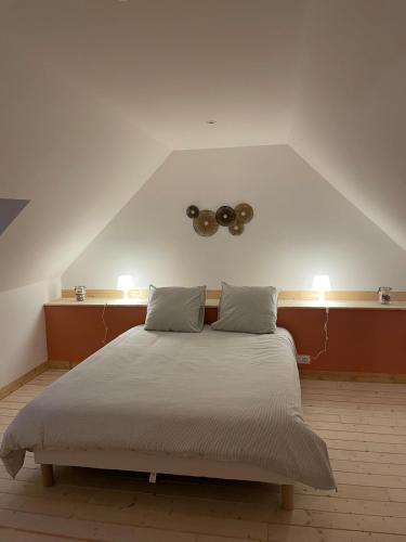 - une chambre avec un lit avec deux oreillers et deux lumières dans l'établissement Les Petits Crapauds Gîte, à Bernesq