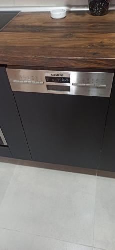 a dishwasher in a kitchen with a wooden counter top at Lux apartment 8, center, free parking in Niš