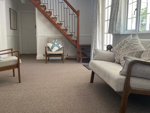 a living room with a couch and a staircase at Rocklea Seaside Cottage in Newcastle