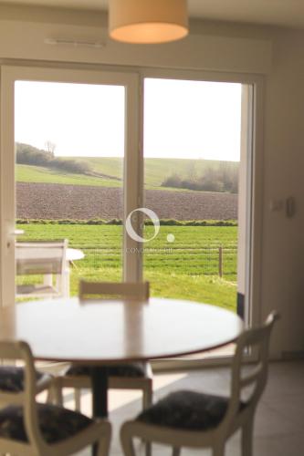 - une table et des chaises dans une pièce offrant une vue sur un champ dans l'établissement COC - L'Envolée, à Wissant