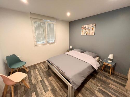 une chambre avec un lit et deux chaises et une fenêtre dans l'établissement Appartement au pied du Haut Koenigsbourg, à Sélestat