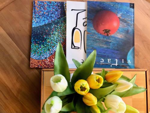 a vase filled with yellow flowers next to two paintings at Wine Hotel Retici Balzi in Poggiridenti