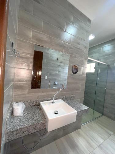 a bathroom with a sink and a glass shower at Hotel Casabella in Chapadão do Sul