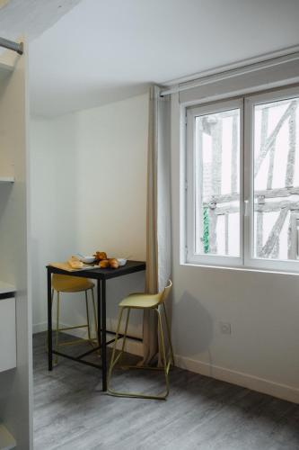 une table et deux chaises dans une pièce avec une fenêtre dans l'établissement Le Muscadelle, à Bergerac