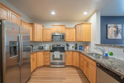 a kitchen with wooden cabinets and stainless steel appliances at Luxurious 3BD - Gym, W-D, Parking - Sleeps 8 in Tempe