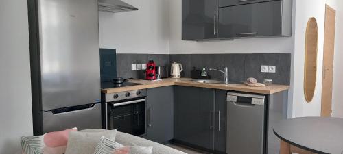 - une cuisine avec des placards noirs, un évier et une table dans l'établissement Dijon en famille - cosy, équipé bébé - 5 mn centre ville, à Dijon