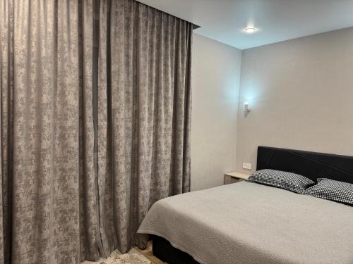 1 dormitorio con cama y cortina grande en Жана Сарыарка, en Karagandá