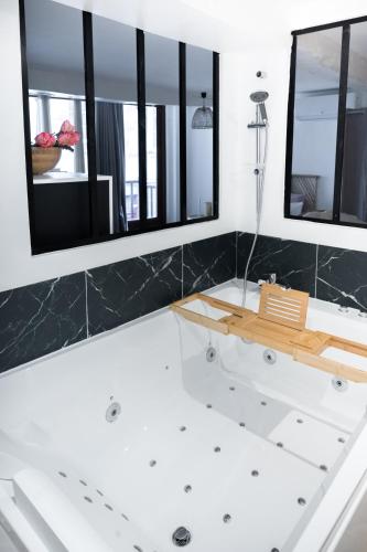 une salle de bain avec une baignoire blanche avec deux miroirs dans l'établissement Le Sauvignon, à Bergerac