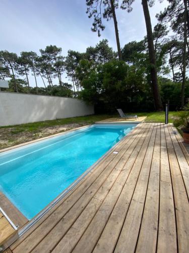 - une piscine avec une terrasse en bois dans l'établissement Villa Dreamland à Seignosse océan, à Seignosse