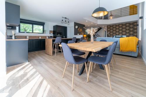 une cuisine et une salle à manger avec une table en bois et des chaises bleues dans l'établissement Les Combettes - Terrasse, Jardin & Proche Lac, à Moyrazès