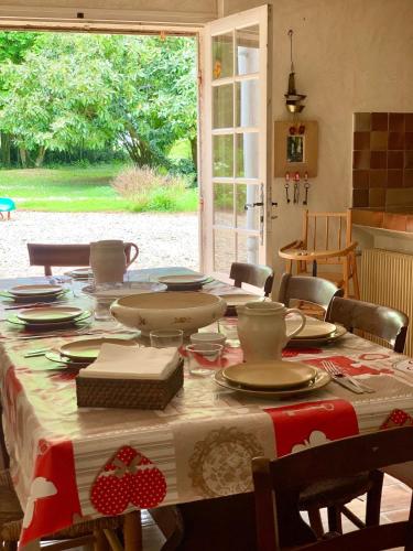 une table avec des assiettes et de la vaisselle en haut dans l'établissement Demeure Familiale, à Preignac