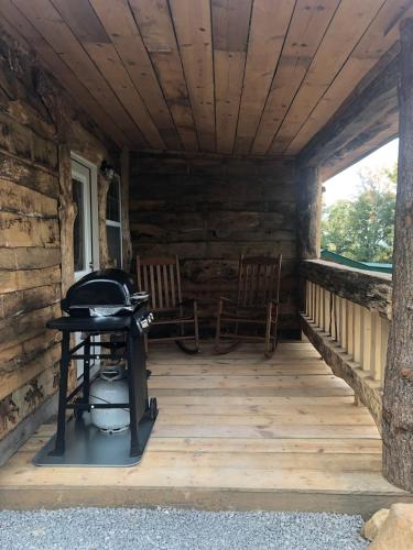a porch of a log cabin with two chairs and a grill at Tree top View 15 in Rising Fawn