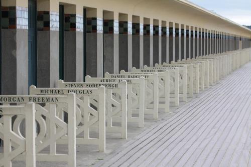 a row of white benches next to a building at Gîte L'Orée de Deauville in Saint-Gâtien-des-Bois