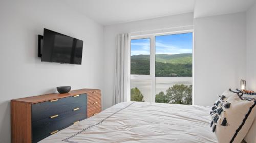 a bedroom with a bed and a tv and a window at Lago by Tremblant Platinum in Mont-Tremblant