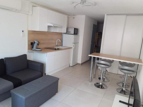 Il dispose d'une cuisine et d'un salon avec un canapé et une table. dans l'établissement Studio Grau du Roi avec piscine, au Grau-du-Roi