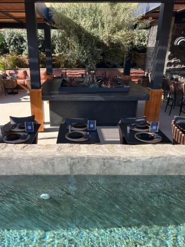a patio with tables and a pool of water at Ftelia Black Villas in Elia