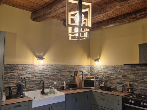 une cuisine avec un évier et un micro-ondes dans l'établissement Maison Auvergnate Spacieuse 170m² - 8 Pers - Nature au Parc des Volcans - FR-1-814-135, à Égliseneuve-dʼEntraigues