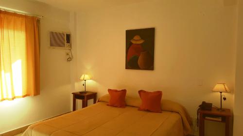 a bedroom with a bed with orange pillows and a painting at Altoparque Hotel Salta in Salta